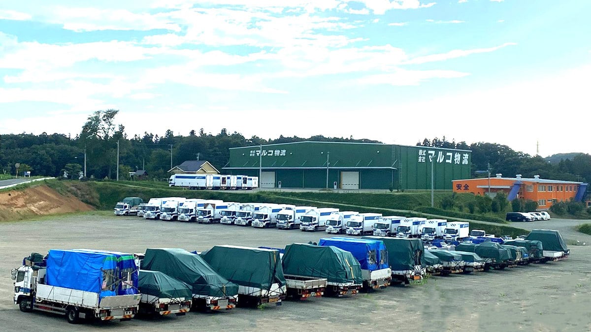 マルコ物流倉庫前に並ぶ丸や運送のトラック